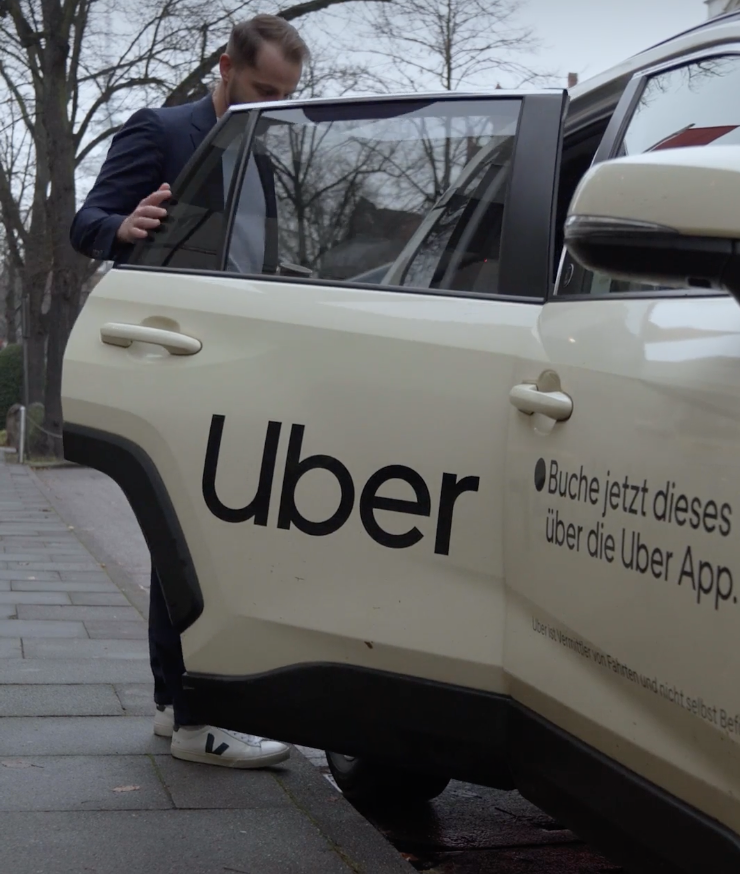 Mann steigt in ein Uber-Fahrzeug mit Uber-Branding